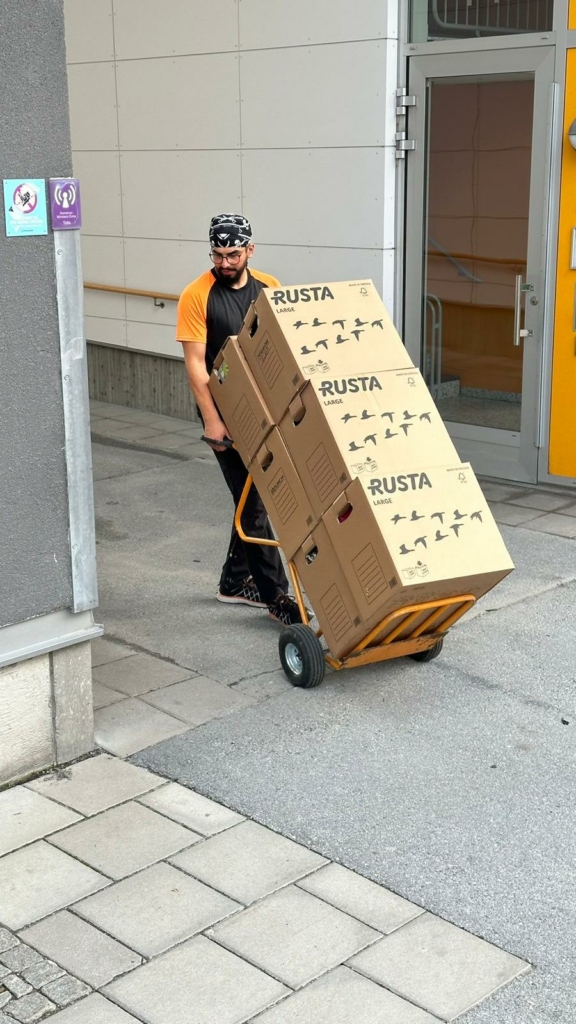 Medarbetare från Scandiflytt kör flyttkartonger med en kärra under en flytt.